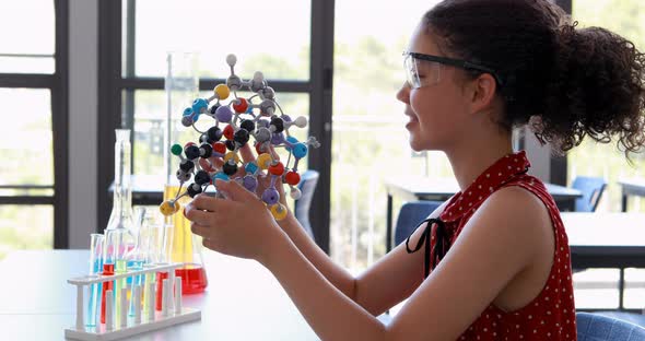 Portrait of happy schoolgirl experimenting molecule model in laboratory