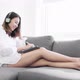 Young Asian woman using digital tablet and headphone on sofa at home living room. Work at home - VideoHive Item for Sale