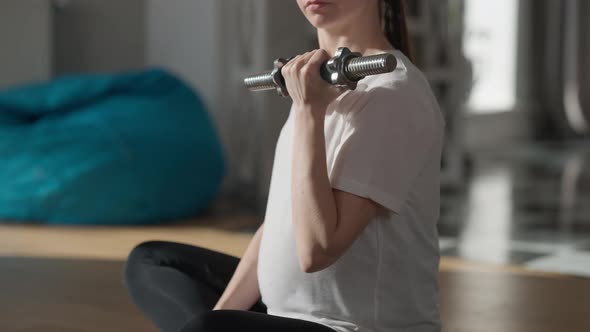 Side View Pregnant Unrecognizable Woman Lifting Dumbbell Sitting on Exercise Mat at Home in the