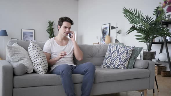 Angry Screaming Man Talking on Phone Sitting on Sofa