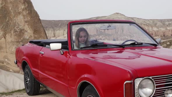 Teen Girl Gets Into a Car Closing the Door and Looking at Camera in Rocks