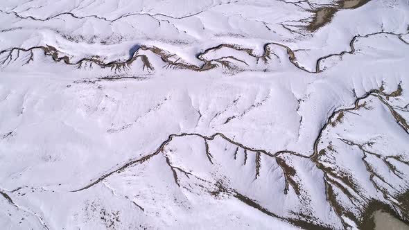 Aerial view flying over cracks in the earths landscape in the snowy desert