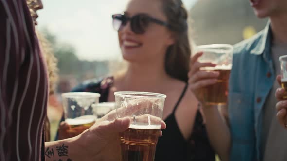 Close up of group of friends spending time together at music festival and toasting with  beer while