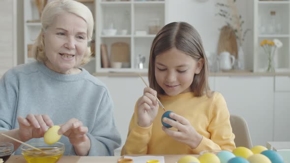 Elderly Woman and Her Granddaughter Decorating Eggs for Easter