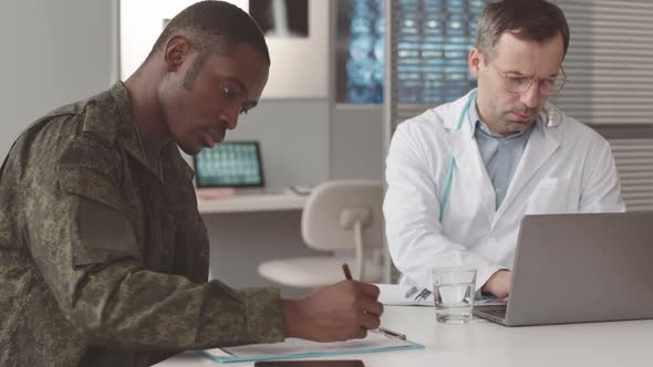 Soldier Filling Out Medical Form at Doctors Office alt