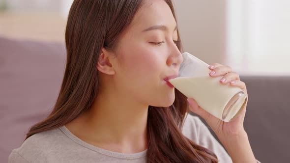 Healthy Young Asian woman Drinking milk with calcium for strong bone at home