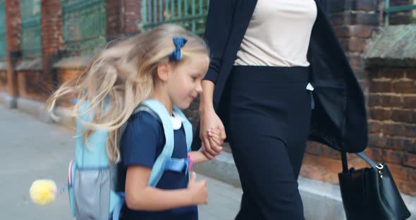 Close Up View of Pretty Child with Long Blond Hair Jumping Happily and Smiling While Holding Mother