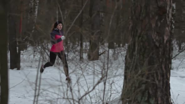 Female Athlete Running Through Winter Forest