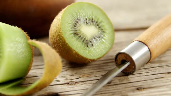 Half section and peel kiwi on wooden table