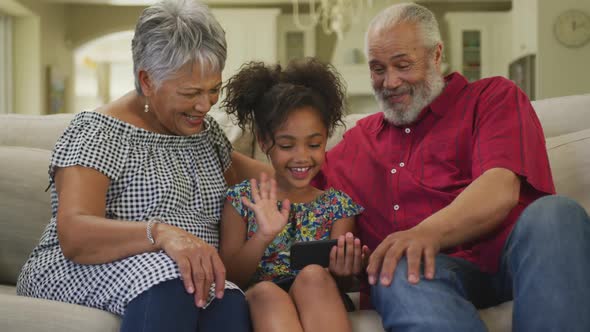 Grandparents and granddaughter using smartphone at home