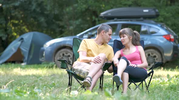 Young happy couple sitting near campsite hugging and talking together.