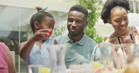 Happy african american family talking and having breakfast in garden