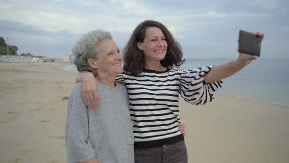 Beautiful Daughter Taking Selfie with Gesturing Elderly Mother