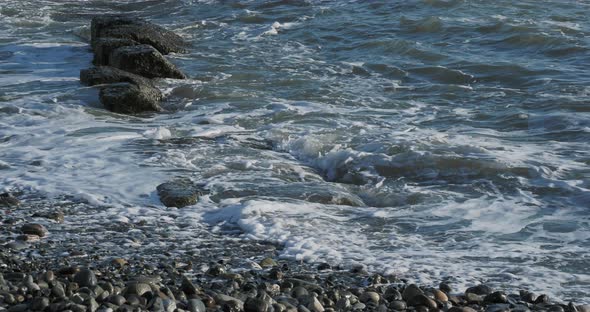 Sea Surf on Rocky Beach. Tranquil Natural Background at Sunny Day. Black Sea, Sochi, Russia.