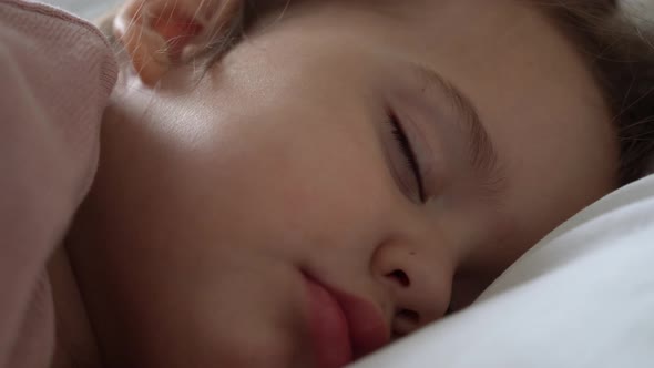 Authentic Cute Little Girl Sleeping Sweetly In Comfortable White and Grey Bed Close Up