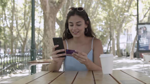 Young Woman Making Payment with Plastic Card Via Smartphone