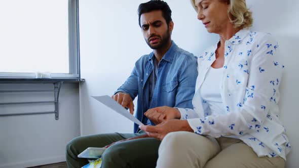 Male and female executives discussing over document