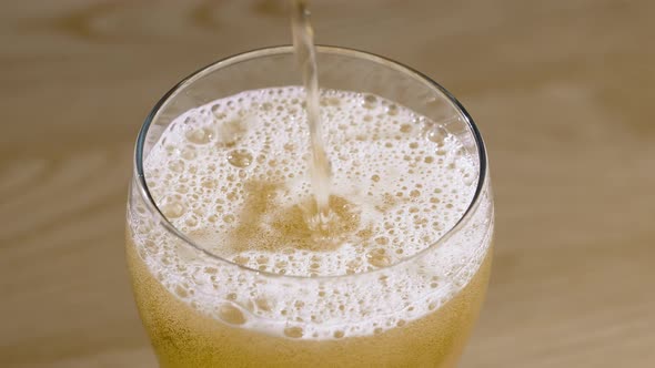 Light Beer is Poured Into a Glass on a Wooden Table