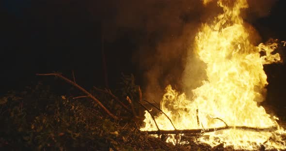 Fire Fighter with Safety Equipment and Axe Extinguishing Fire in Forest at Night