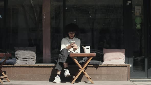 Mixed race girl uses cell phone while eating outdoors