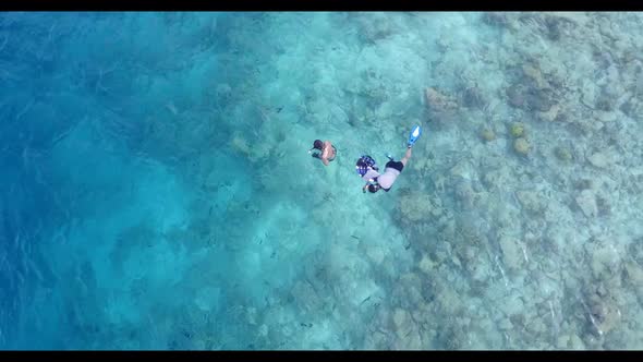 Boy and girl relax on perfect lagoon beach break by blue green water with white sand background of t