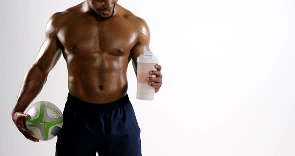 American football player holding a water bottle and rugby ball