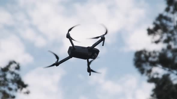 Drone Hangs in the Air Against the Blue Sky, View From Below. Slow Motion