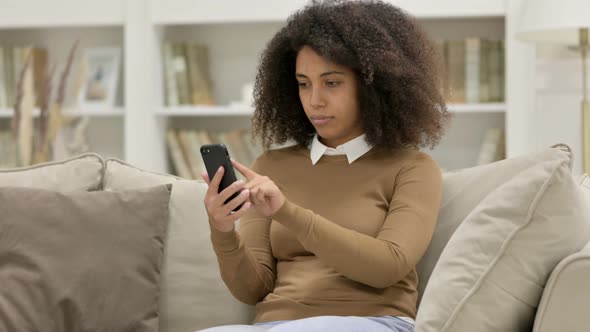 Young African Woman Using Smartphone on Sofa