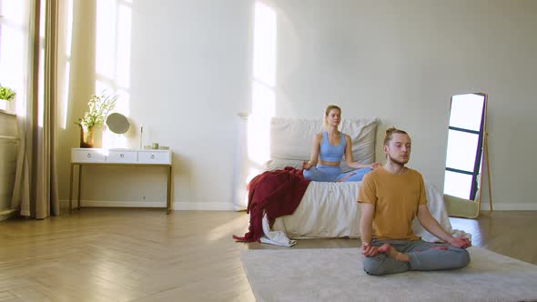 Footage of a Young Couple Meditating in Home Interior