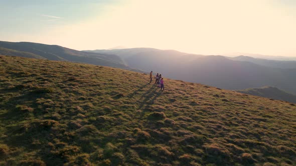 Flying Over Group of Happy Hikers Enjoying the Sunny Morning From the Mountain Top