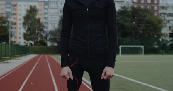 Portrait of Disabled Serious Man with Prosthetic Running Blade Standing at Sports Field