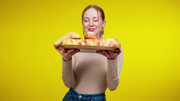 Middle Shot of Charming Slim Redhead Woman Posing with Tray of Bread and Croissants at Yellow