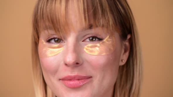 Beautiful Smiling Woman with Short Hair in Gold Eye Patches Looking in Camera and Smiling Over