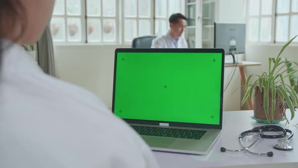 Close Up Asian Woman Doctor Is Using Laptop Computer With Mock Up Green Screen Display In Workplace