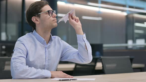 Young Man Holding Paper Plane in Office