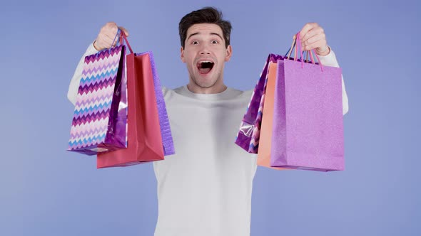 Handsome Man Holds Shopping Paper Bags on Violet Studio Background