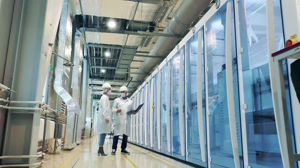 Two Specialists are Observing Factory Cabinets and Pipes