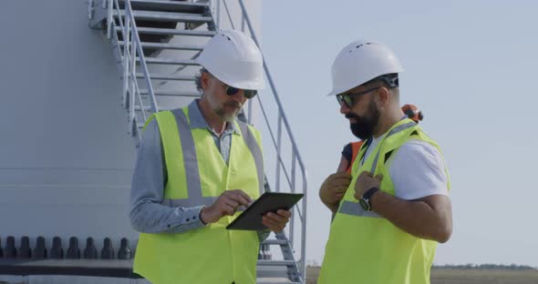 Male Engineers Talking on Wind Farm