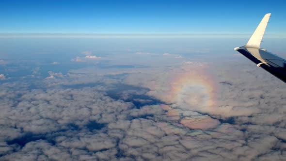 Incredible circle halo rainbow effect reflected over clouds. Airplene aerial view