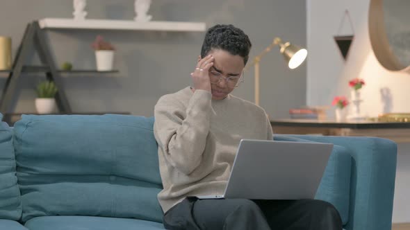 African Woman with Laptop Having Headache on Sofa