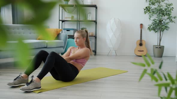 Slow Motion of Female Student Exercising Abs on Yoga Mat in Modern Apartment