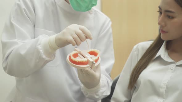 A caucasian dentist man, people showing how to use dental floss with typodont teeth model