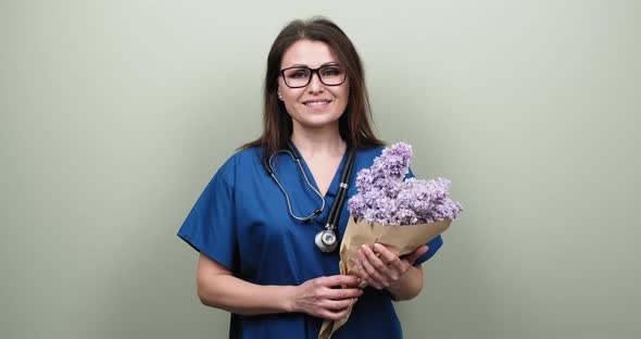 Portrait of Female Doctor Showing You Victory Sign, Happy Smiling Medic with Bouquet of Flowers 