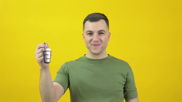 Caucasian Middleaged Man in a Green Tshirt Happily Shows a Car Key in His Hand