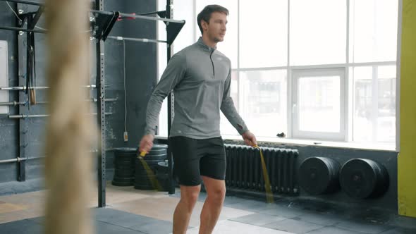Handsome Sportsman Skipping with Jumping Rope Indoors in Gym Focused on Cardio Exercise