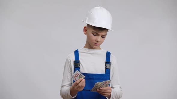 Boy in Builder Contractor Uniform Counting Money Looking at Camera with Satisfied Facial Expression