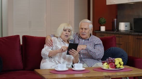 Senior Grandparents Couple Talking and Using Digital Tablet Computer at Home. Coronavirus Lockdown