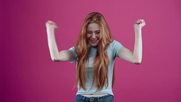 The Redhead Teenager Displays a Wide Smile Enjoying Her Results By Raising Her Hands Up Like a Real