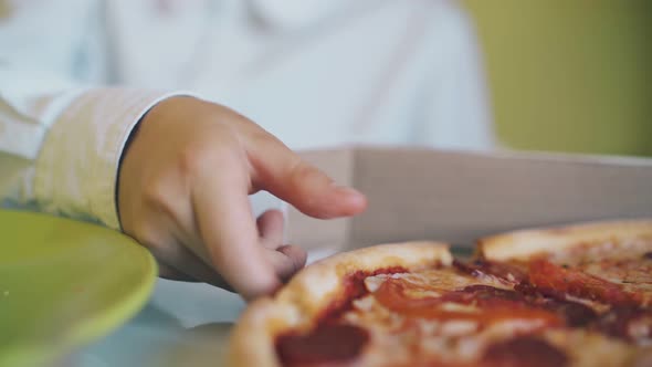 Boy in Shirt Bites Delicious Pizza at Table Close View