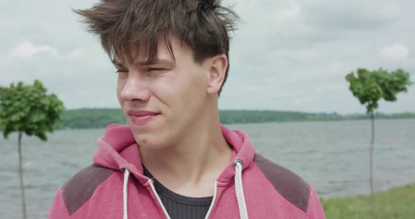 Handsome Young Man Looks Around and at Camera at the Lake on Nature